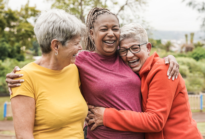 Happy multiracial senior women having fun together outdoor - Elderly generation people hugging each other at park