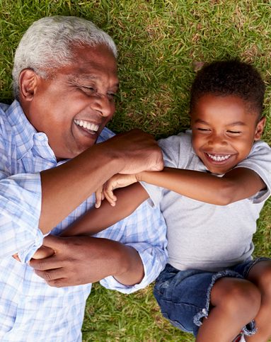 Grandfather and grandson play lying on grass, aerial view